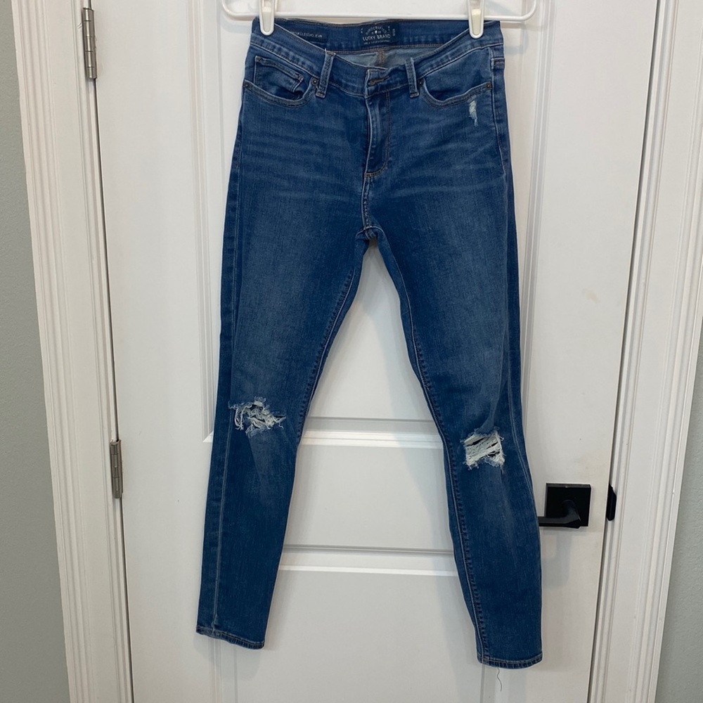 Medium wash Lucky jeans with destroyed knees.